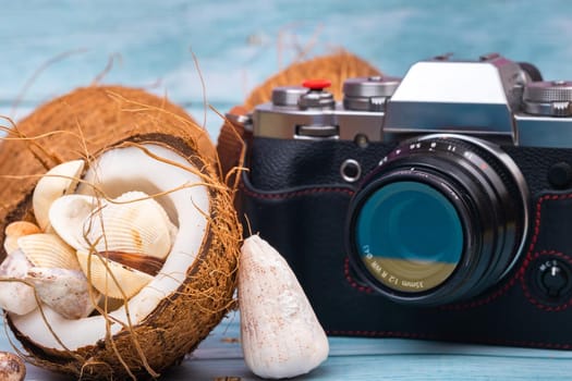 camera,coconuts and shells on a blue wooden background.Marine theme.