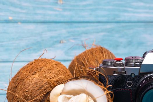 camera,coconuts and shells on a blue wooden background.Marine theme.