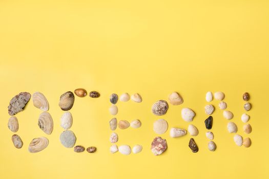 The inscription of the word ocean made of shells on a yellow background.Travel concept.
