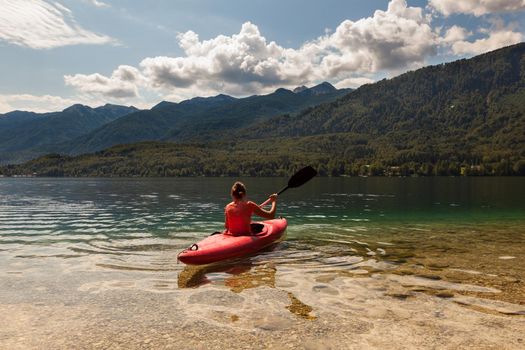 Girl kayaking in the scenic Bohinj lake, Slovenia