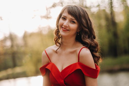 Spring Portrait of a laughing girl in a long red dress with long hair walking in the Park in the woods