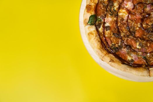 Delicious large pizza with bacon and spinach on a yellow background.