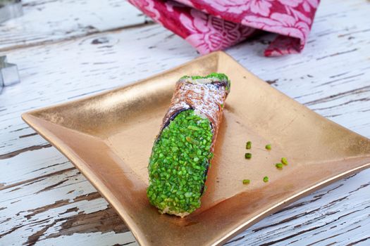 Cannolo, the typical Sicilian pastry on a gold plate