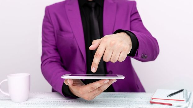 Businessman in a Pink jacket sitting at a table holding a mobile phone