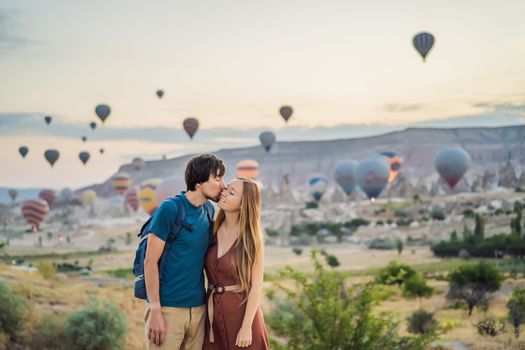 Tourists couple man and woman looking at hot air balloons in Cappadocia, Turkey. Happy Travel in Turkey concept. Couple man and woman on a mountain top enjoying wonderful view.