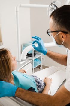 Dentist showing dental veneer teeth implant to woman patient in dental clinic. Dentistry. Consultation with dentist about tooth implantation and whitening