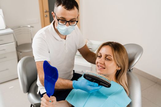 Teeth whitening. Patient looking at teeth color shades guide. Dentistry. Doctor checking tooth color matching samples in dental clinic