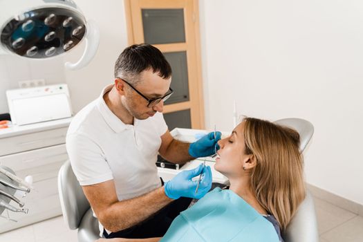 Dentist examines teeth of woman for treatment of toothache. Pain in teeth. Consultation with dentist in dentistry