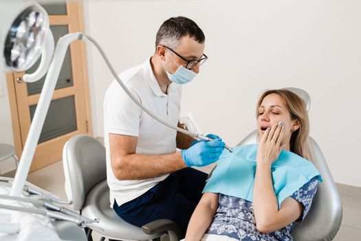 Attractive woman afraid of dentist. Dentist consults frightened girl in dentistry. Treatment of teeth and toothache in dentistry