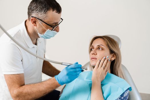 Attractive woman afraid of dentist. Dentist consults frightened girl in dentistry. Treatment of teeth and toothache in dentistry