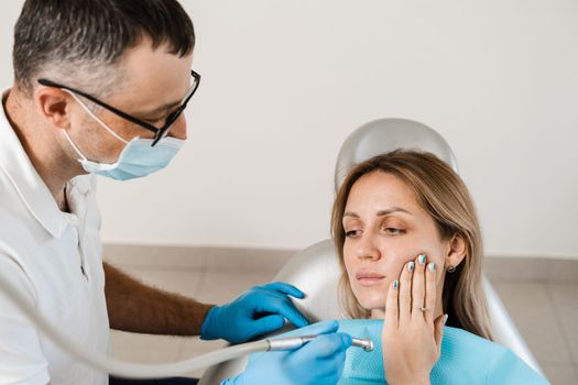 Woman with toothache on consultation and treatment at the dentist in stomatology. Dentist treats caries teeth for girl