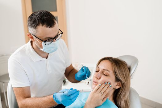 Woman with toothache on consultation and treatment at the dentist in stomatology. Dentist treats caries teeth for girl