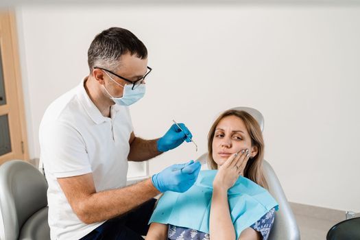 Dentist examines woman with toothache at consultation and treatment at the dentist in dentistry. Dentist treats caries teeth for girl