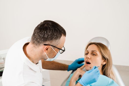 Dentist examines teeth of woman for treatment of toothache. Pain in teeth. Consultation with dentist in dentistry