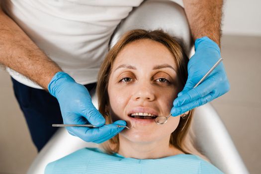 Dentist examines girl mouth and teeth and treats toothaches. Happy woman patient of dentistry. Consultation with dentist at dentistry. Teeth treatment