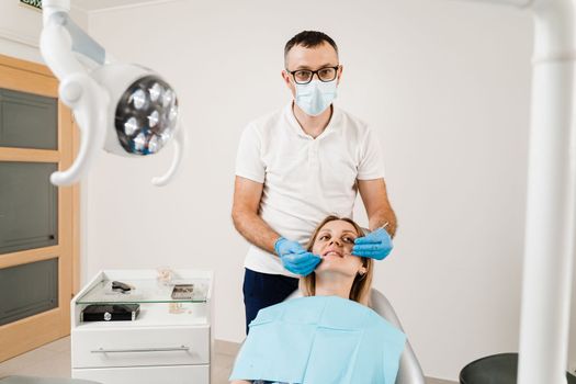 Consultation with dentist at dentistry. Teeth treatment. Dentist examines girl mouth and teeth and treats toothaches. Happy woman patient of dentistry