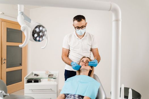 Dentist examines girl mouth and teeth and treats toothaches. Happy woman patient of dentistry. Consultation with dentist at dentistry. Teeth treatment