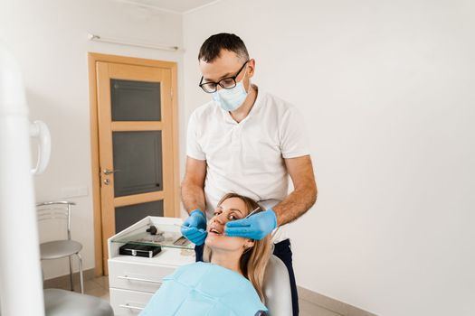 Dentist examines girl mouth and teeth and treats toothaches. Happy woman patient of dentistry. Consultation with dentist at dentistry. Teeth treatment