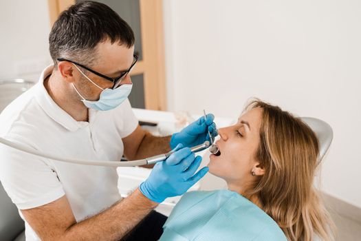 Dental drill. Dentist drilling teeth of woman in dentistry clinic. Dental filling for girl patient