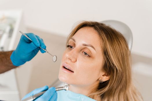 Dentist examines girl mouth and teeth and treats toothaches. Happy woman patient of dentistry. Consultation with dentist at dentistry. Teeth treatment