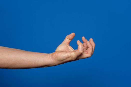 Strong man's hand in the form of a claw containing anger and aggressiveness isolated on blue background.