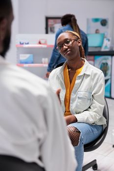 Pharmacy consultation, african american customer talking with pharmacist, sitting in drugstore. Client and chemist communication, pharmaceutical service, medical check up