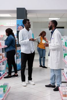 African american customers purchasing medicaments in pharmacy store, pharmacist recommending man vitamin c in drugstore, woman buying prescription treatment, all black team