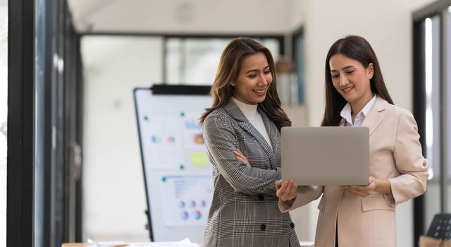 Atmosphere in the office of a startup company, two female employees are discussing, brainstorming ideas to working on summaries and marketing plans to increase sales and prepare reports to managers...