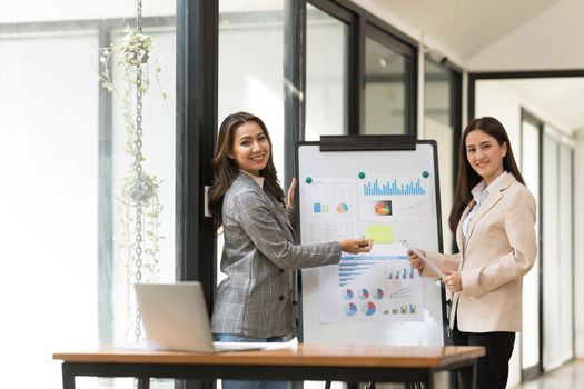 Atmosphere in the office of a startup company, two female employees are discussing, brainstorming ideas to working on summaries and marketing plans to increase sales and prepare reports to managers...