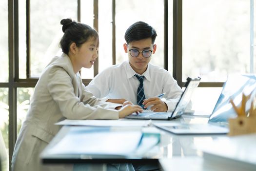 Businesspeople or office workers are working together on project. They are discussing, sharing the ideas, planning, and analyzing the business strategy. And set up the budget for financial plan by using laptop and calculator.