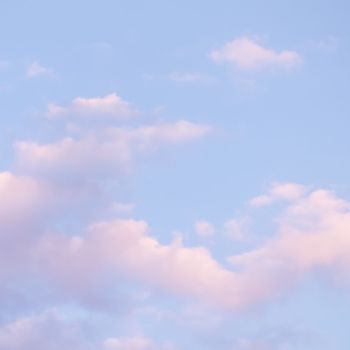 Blue sky background with white and pink clouds at sunset. High quality photo