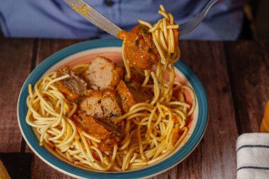 close-up of a man eating a plate of meatballs with spaghetti