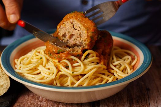 close-up of a man eating a plate of meatballs with spaghetti