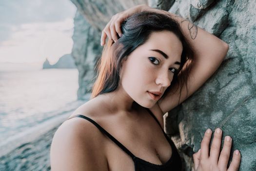Portrait of cheerful female climber ascending a rock. The athlete girl trains in nature. Woman overcomes difficult climbing route.