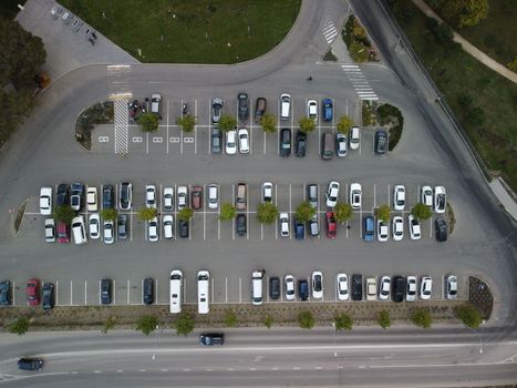 Busy large modern carpark with symmetrical roads rows of parking bays lots of symmetry and colours aerial view from drone up above looking down
