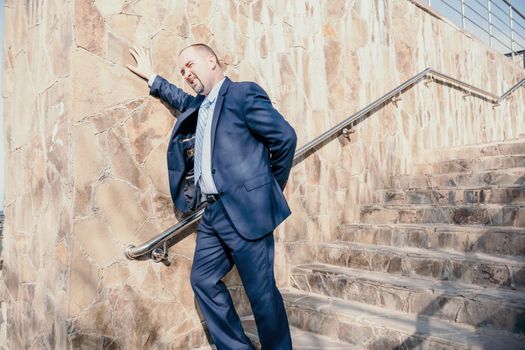 Portrait of a senior professional man in a suit with various problems. A middle-aged businessman with a briefcase descends the stairs.