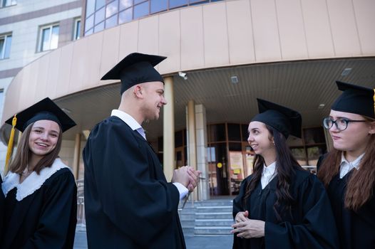 Happy students in graduate gown communicate in sign language