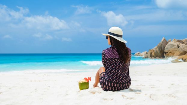 Women with a coconut drink on a tropical beach La Digue Seychelles Islands.