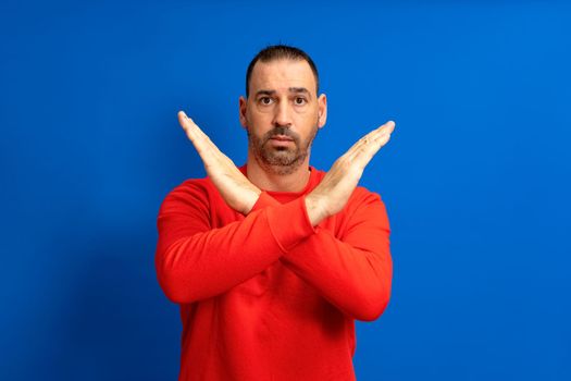 Photo of strict hispanic bearded man showing enough arms denial of forbidden symbol isolated over blue colored background