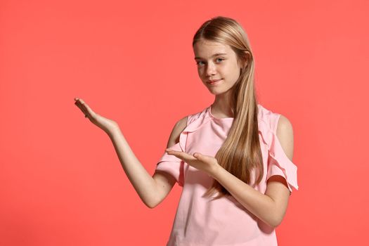 Studio portrait of a gorgeous blonde young lady with a long hair, in a rosy t-shirt, standing against a pink background in various poses. She expresses different emotions posing sideways right in front of the camera, smiling and advertising something.