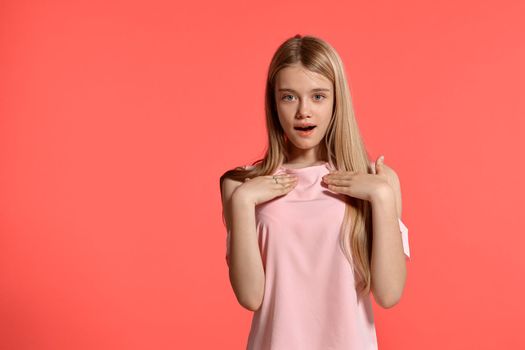 Studio portrait of a gorgeous blonde teenager with a long hair, in a rosy t-shirt, standing against a pink background in various poses. She expresses different emotions posing right in front of the camera, wondered and looking like getting a present.