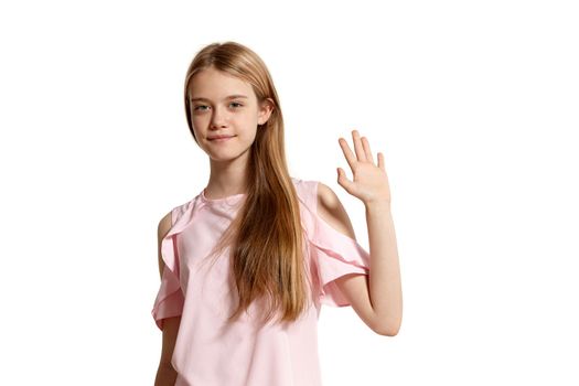 Studio portrait of a cute blonde teenager in a pink t-shirt isolated on white background in various poses. She expresses different emotions posing right in front of the camera, smiling and saying hi.