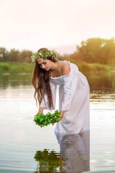 Woman in white dress in the water. Art Woman with wreath on her head in river. Wet witch Girl in the lake, mystical mysterious woman. Wreath on her head, Slavic traditions and paganism