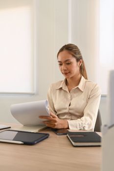 Gorgeous businesswoman preparing report, analyzing work results at her office desk.