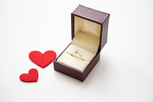 Beautiful red hearts on a white background together with a ring in a box. Marriage proposals