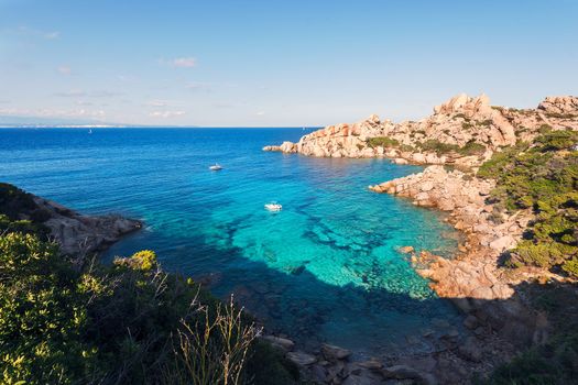 panoramic view of a creek with anchored boats. Vegetation and rocks surround it, scenic place for vacationers and summer holidays, bright colors. Capo Testa, Santa Teresa di Gallura, Sardinia, Italy