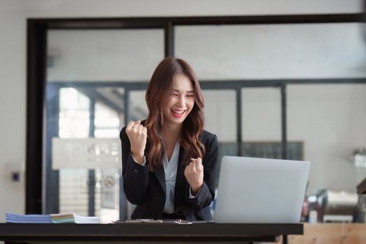 Portrait of Happy asian business woman with laptop computer in office. Woman in suit at office.