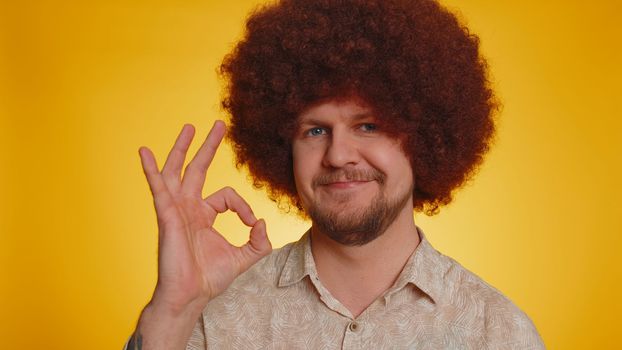 Ok. Joyful happy man with lush Afro hairstyle coiffure looking approvingly at camera showing approve feedback gesture, like sign positive something good. Young hipster guy boy on yellow background