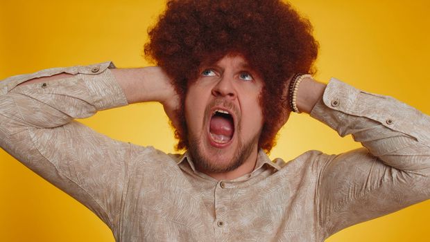Dont want to hear and listen. Frustrated annoyed irritated man afro hairstyle covering ears and gesturing no, avoiding advice ignoring unpleasant noise loud voices. Hipster guy on yellow background