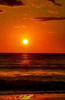 Beautiful stunning colorful and golden sunset in yellow orange red on beach and big wave panorama in tropical nature in Zicatela Puerto Escondido Oaxaca Mexico.